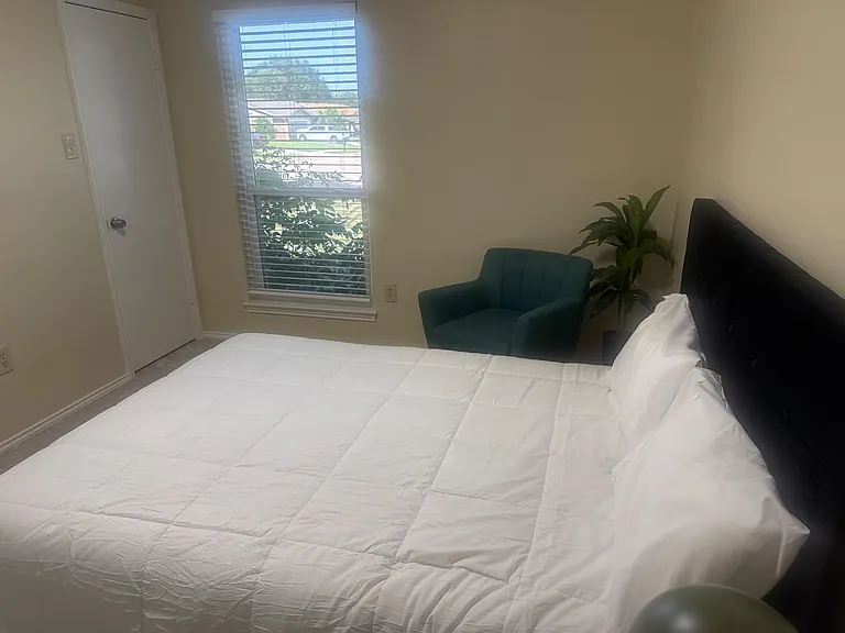 Private bedroom with a large window, upholstered headboard, and space for a sitting chair, plus a closet for storage.