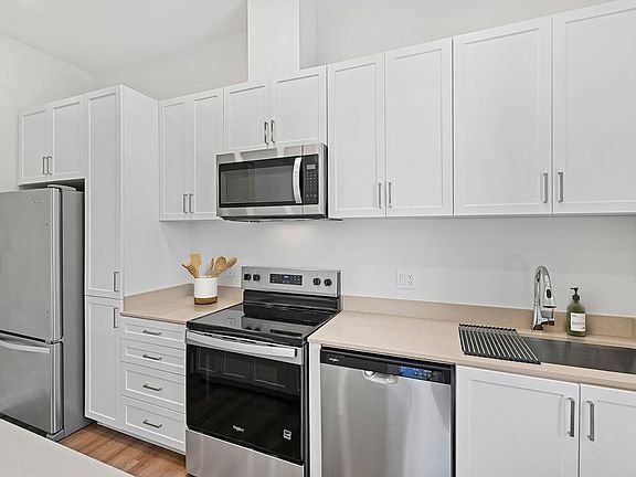 Freestanding Home kitchen with stainless steel appliances, white cabinetry, beige quartz countertops, and hard-surface flooring