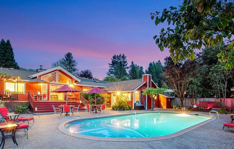 Large backyard with pebbled surfaced pool, hot tub, outdoor shower and matured fruit trees.