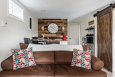 The lower level features a spacious, fully furnished living room designed for comfort and relaxation, complete with modern decor and direct walkout access, seamlessly connecting indoor comfort with outdoor convenience.