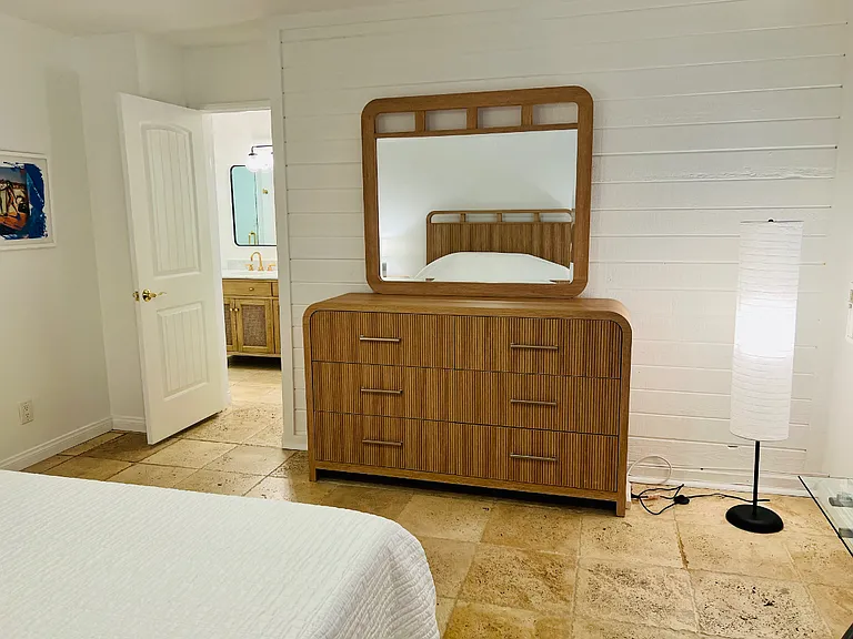 Primary bedroom chest of drawers, mirror and the door leading to the primary bathroom