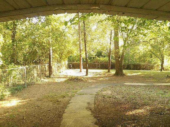 View through Carport to backyard sidewalk leads to rear door