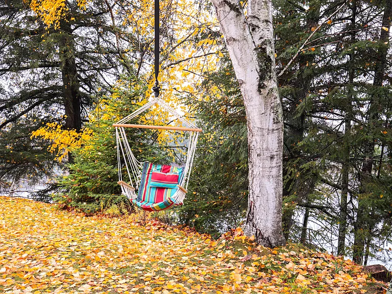 chair swing out back door, next to a romantic table for two, a grill and fire cauldron, dining tent. Lake front property rental Upper Peninsula #VacationRental