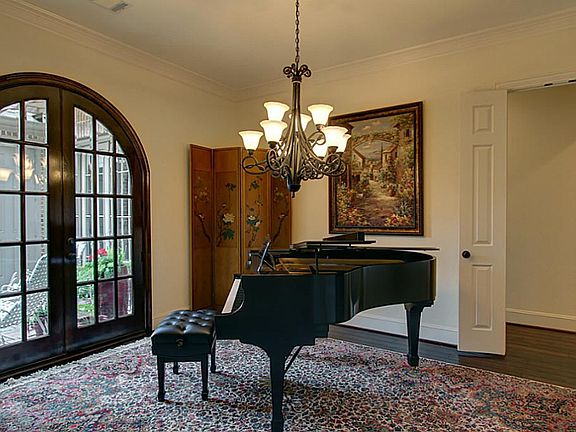 The formal dining room has a beautiful iron chandelier, gorgeous arched french doors to the courtyar