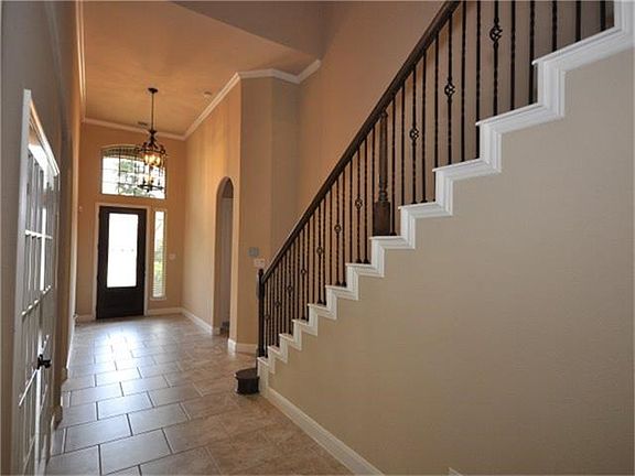 The entry is freshly painted, with high ceiling, tile flooring through out and the iron work on the stairs.