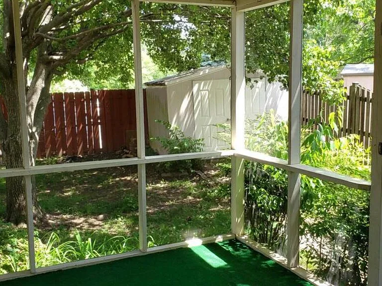 sunroom overlooking fenced backyard with many mature trees