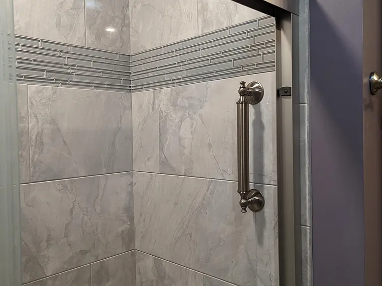 master bath shower door, grab bars at front and rear shower walls. Wall tile coordinates with floor tile.