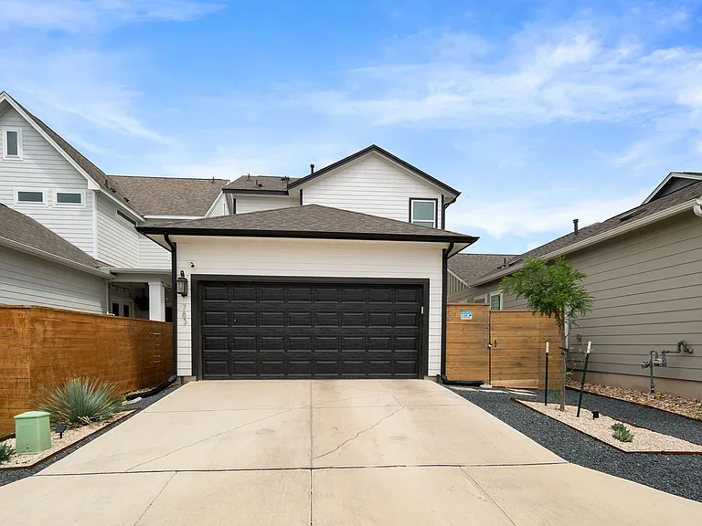 Back of the home features xeriscaped landscaping and upgraded garage door