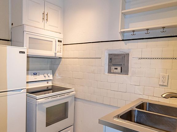 Kitchen: Full sized refrigerator, stove range and microwave above. Double kitchen sink. Includes hanging storage shelf.