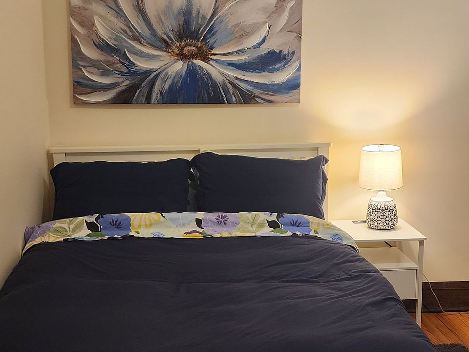 Bedroom with full-sized bed, desk, chair, cabinet, rolling cart, nightstand, two lamps, an accent chair and large closet.