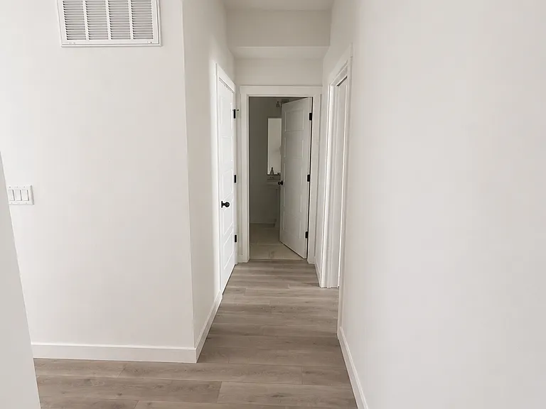Hallway to half bath and primary bedroom