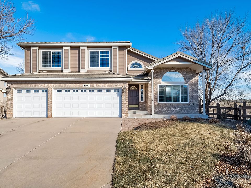Striking front elevation with timeless brick accents, vaulted entry, and abundant natural light. Three-car garage and extended driveway offer everyday convenience, while the quiet setting and open-space backdrop enhance curb appeal and privacy.