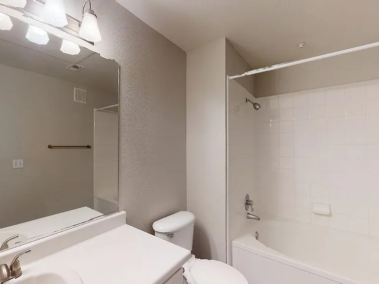 Apartment bathroom with large soaking tub and wood-style flooring.