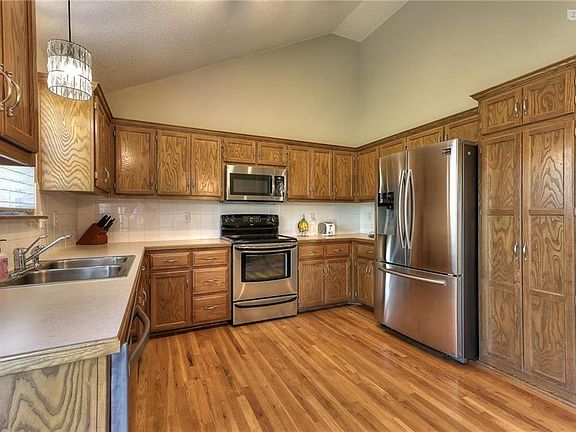 Kitchen features wood floors, stainless steel appliances and lots of cabinets