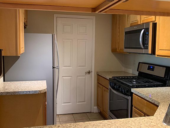 Kitchen with stainless steel appliances and door to washer/dryer/utility closet.