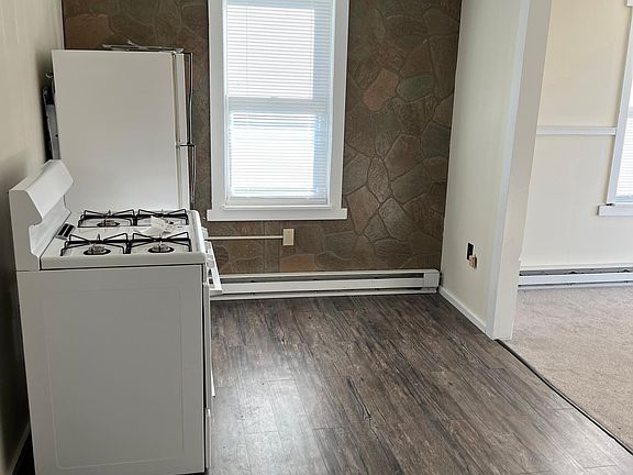 Kitchen with gas stove, refrigerator, and vinyl flooring.