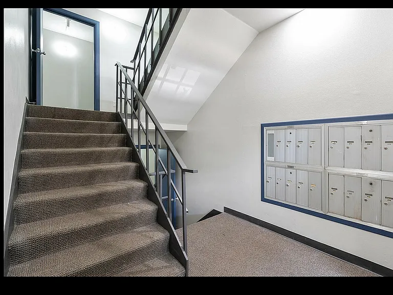 Bright and inviting apartment stairwell featuring modern railing and convenient mailboxes, promising a welcoming entrance.