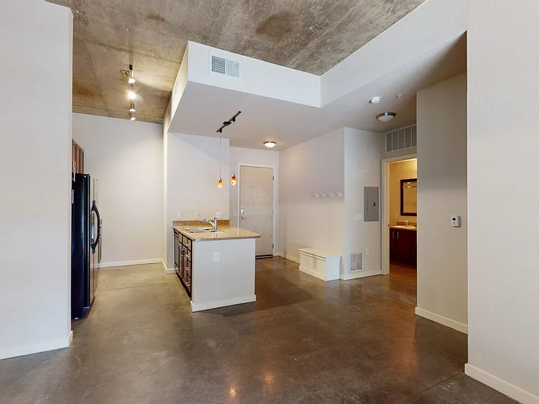 Apartment kitchen with granite countertops and polished concrete flooring.
