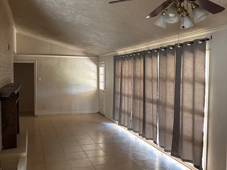 Living room with large windows overlooking covered patio and peaceful backyard.