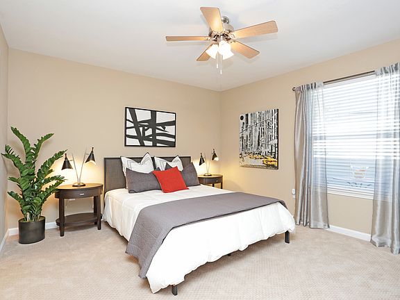 Spacious bedroom with ceiling fan and plush carpeting.