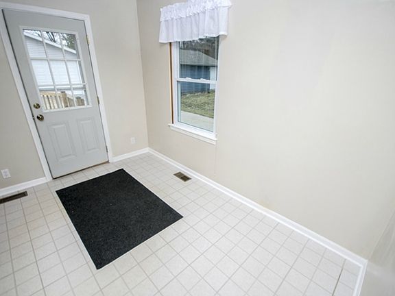 At the back of the home sits the large eat-in kitchen with linoleum floors.  This photo shows the dining space (11x8) and the back door leading to a large deck. Also located in this area is the access panel for the home-security system.