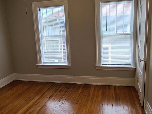 Large bedroon with 2 large windows ad hardwood floors.