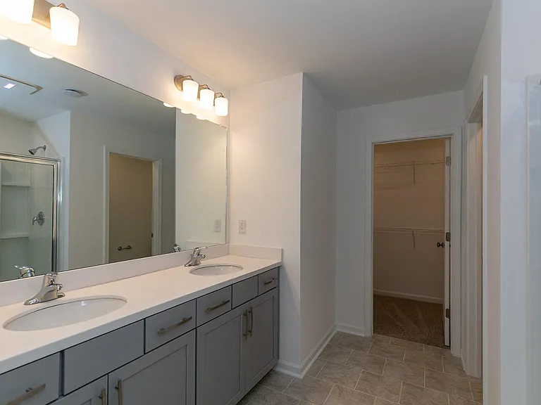 Primary bathroom with double vanity, walk-in shower and walk-in closet.