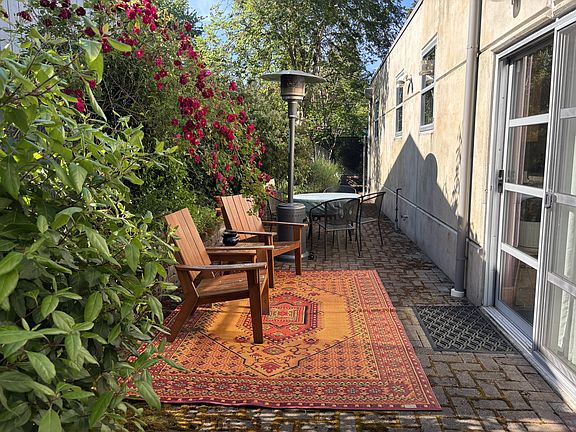 Back patio including pavers, raised brick garden beds, 3 separate sitting spaces surrounded by trees, shrubs, and flowers. Tons of privacy, shade, sun pockets, and plant heaven.