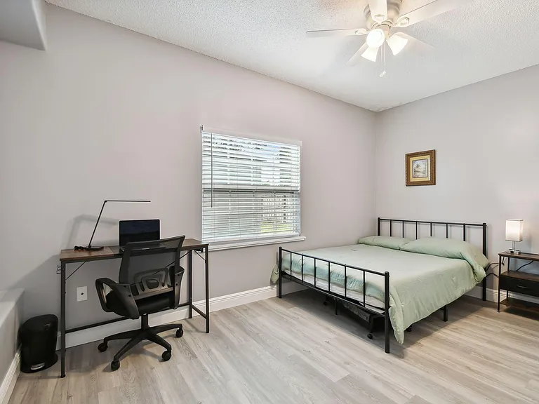 Full size cozy bed, with end table, light, office desk, chair and light as well as storage container under the bed.