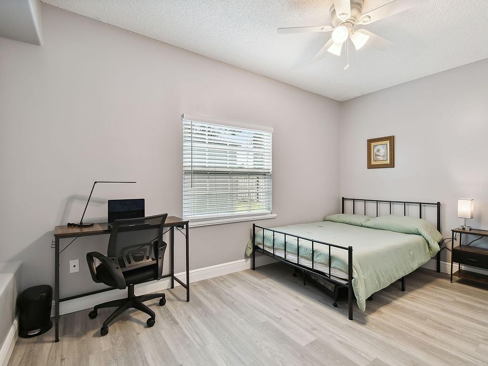 Full size cozy bed, with end table, light, office desk, chair and light as well as storage container under the bed.