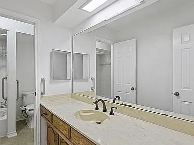 Bathroom vanity with a wide countertop, dual mirrors, and overhead skylight for added illumination and functionality.