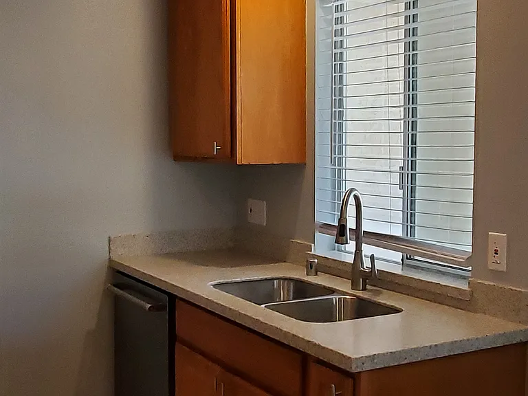 Kitchen with stainless steel sink, window, tile floors, & KitchenAid dishwasher