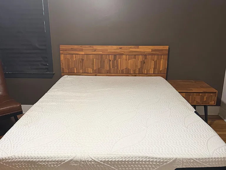 Furnished bedroom with a full-size bed, matching nightstand, and window with blinds for light and privacy.