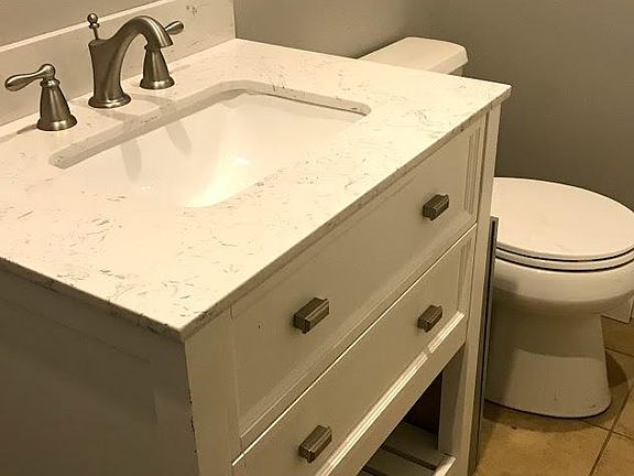 New bathroom vanity and toilet, tiled shower, stacked washer/dryer in bathroom.