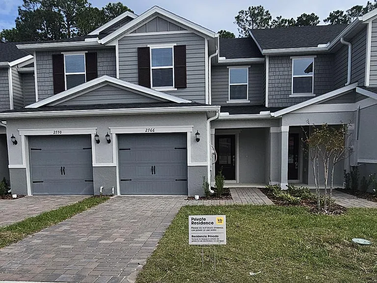 Exterior view of this move-in ready townhome in The Sanctuary at Clermont, featuring an attached garage, modern facade, and well-maintained landscaping in a quiet community.