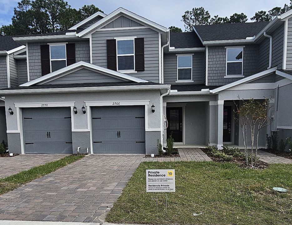 Exterior view of this move-in ready townhome in The Sanctuary at Clermont, featuring an attached garage, modern facade, and well-maintained landscaping in a quiet community.