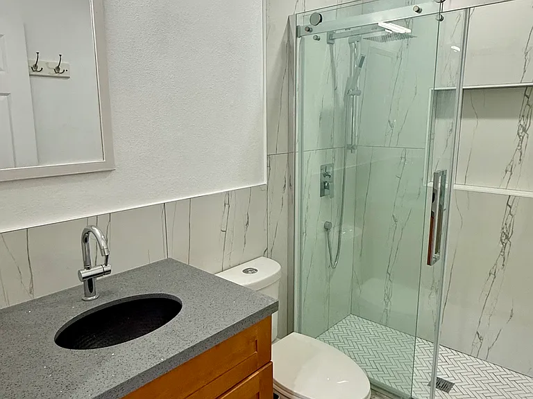 Brand new bathroom with tile floor and walk in shower with glass door.