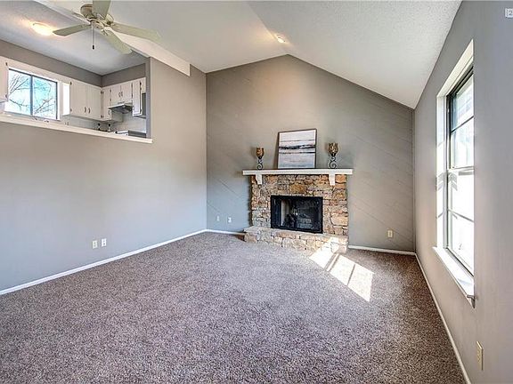 Stone fireplace in the Living Room with a ceiling fan.