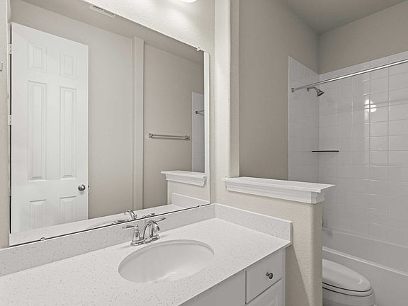 The secondary bath features a large vanity and shower tub combo with tile surround