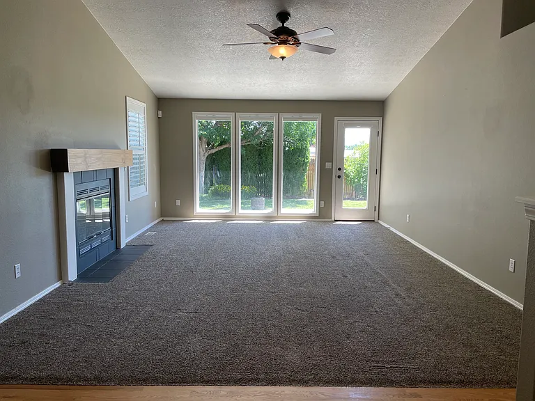 Living room with large windows overlooking mature landscaped backyard