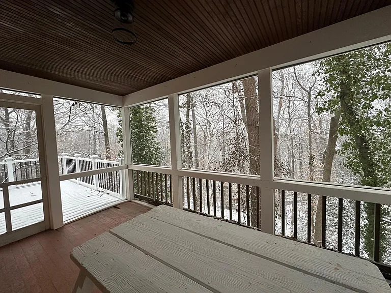 Sunroom on right side facing forest winter view.