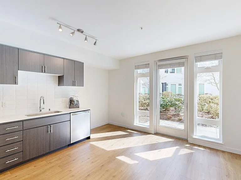 Apartment Kitchen with Stainless Steel Appliances, Dining and Living Room with Wood-Style Flooring.