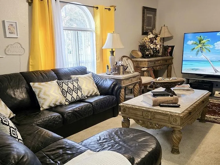 Inviting living room with a large sectional, arched window with drapes, and ample space for relaxing and entertaining.