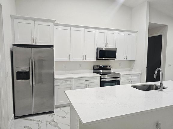 Modern Kitchen with White Cabinetry, Stainless Steel Appliances, Quartz Countertops, and Large Island