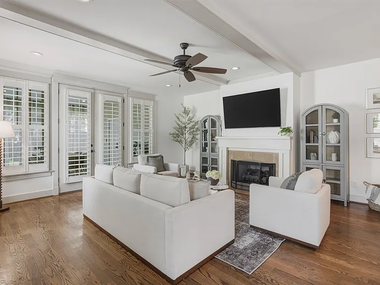 Beautifully designed living room with a fireplace, ceiling fan and plenty of comfy seating. Smart TV, wood floors, and easy flow into the kitchen.