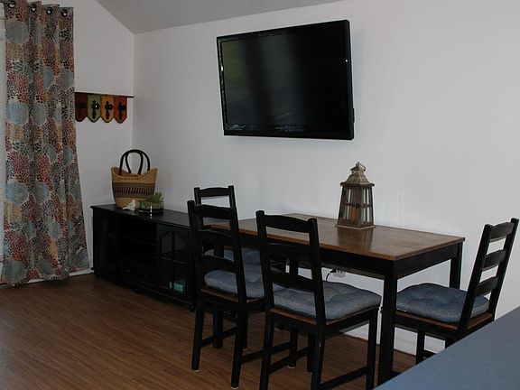 Living Room- layout shows couch, tv stand, small dining table. Double doors open to back balcony.