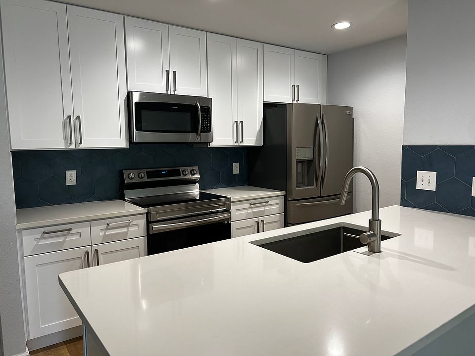 Kitchen with stainless steel appliances, large deep kitchen sink, designer backsplash, and eat-in quartz countertop