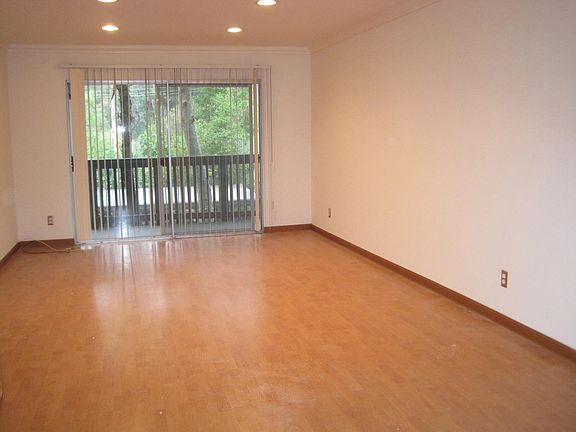Recessed lighting, laminate wood floors, balcony with view of trees and small entry road