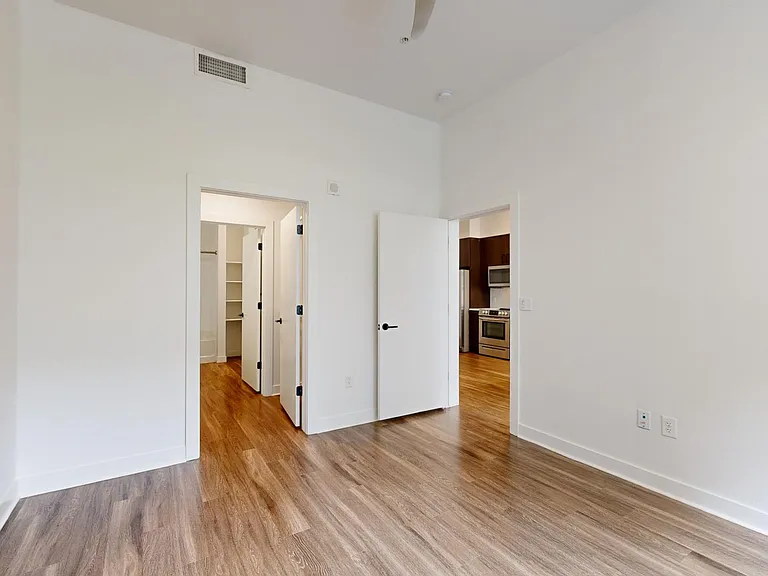 Spacious apartment bedroom with large closet, attached bathroom, and wood-style flooring.