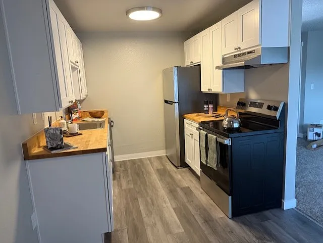 Newly Renovated kitchen with white shaker cabinetry and new stainless steel appliances. Butcher block countertops give this a modern update!